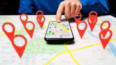 mobile phone with map on top of map with location pins